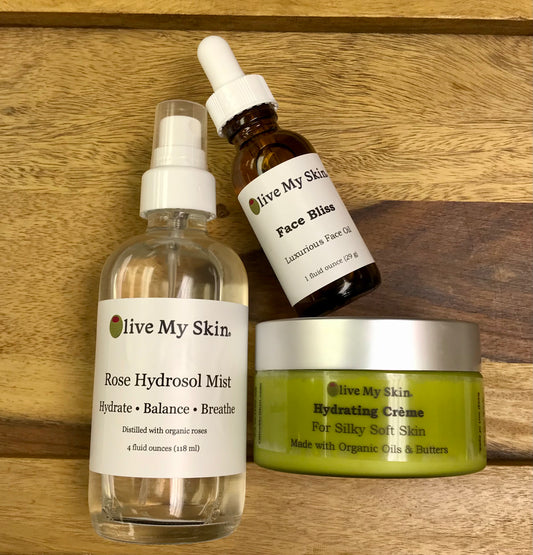 Skin care products oils. spray bottle of rose hydrosol mist, dropper bottle of a face oil, green jar of creme